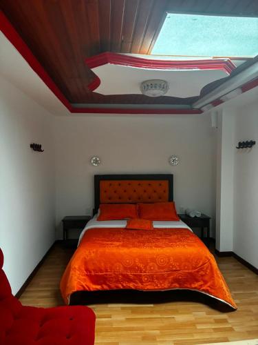 a bedroom with a bed with an orange blanket at Hotel Tropical Club in Estación El Salto