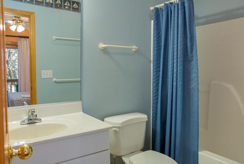 a bathroom with a toilet and a sink with a blue shower curtain at Dragonfly in Southern Shores