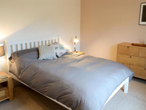a bedroom with a bed and a dresser with a lamp at Morlich in Gairloch
