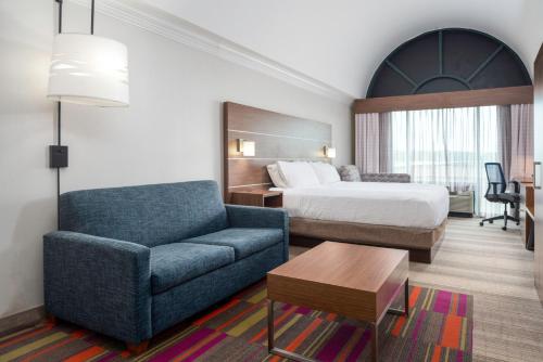 a hotel room with a bed and a blue couch at Holiday Inn Express & Suites Macon - I-475 by IHG in Macon