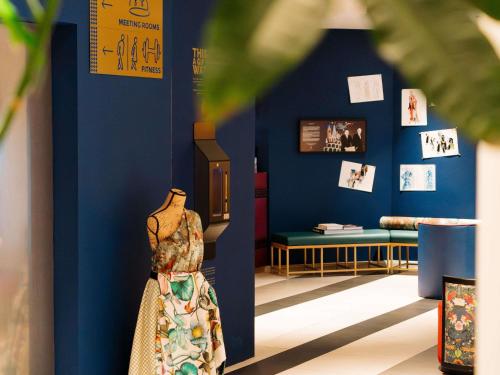 a room with a blue wall with a dress and a bench at Maek Hotel Antwerp Central - Accor Handwritten Collection in Antwerp