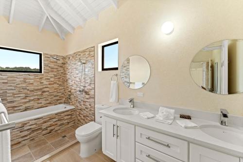 a bathroom with a sink toilet and a mirror at Mullins Bay View - 4 Bed - Sea View, Infinity Pool in Saint Peter