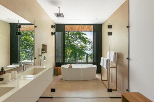 a bathroom with a tub and a large window at Tenowi Villa in Mal País