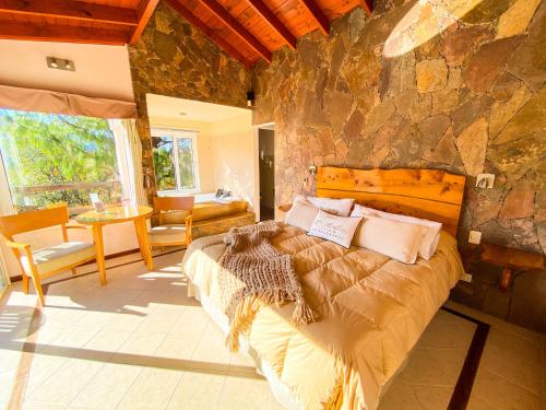a bedroom with a large bed and a stone wall at Balcones de La Cumbrecita in La Cumbrecita