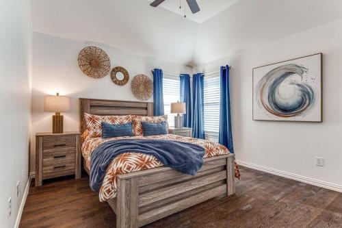 a bedroom with a bed and a window with blue curtains at 5Br Lux! Pool, Games & Theater in Rowlett