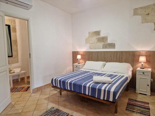 a bedroom with a bed with a blue and white striped blanket at Miramare Residence in Favignana