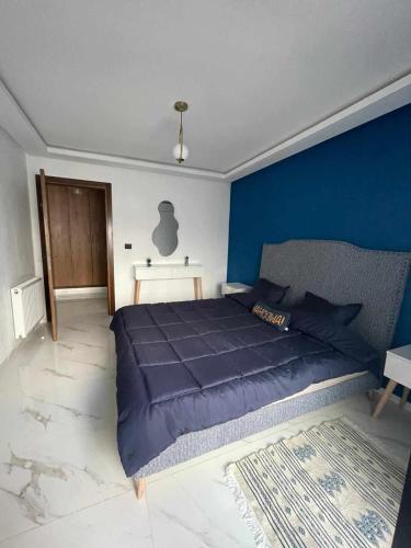 a bedroom with a large bed with a blue wall at Cerises in El Aouina Station