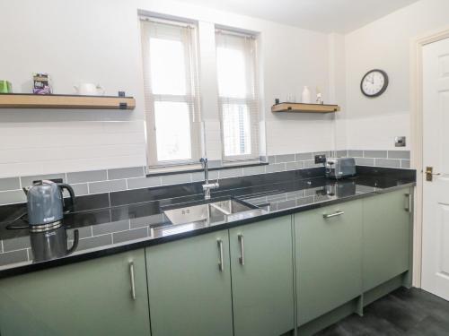 a kitchen with green cabinets and a sink at Win Hill View in Bamford