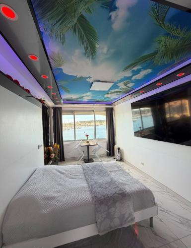 a bedroom with a large bed with a ceiling with a mural at 240 Magnifique Appart Deluxe vue mer in Cap d'Agde