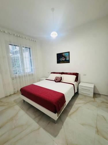 a white bedroom with a large bed with a red blanket at Casa di Ale in Rapallo