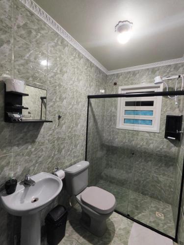 a bathroom with a toilet and a sink and a shower at Casa temporada in Joinville