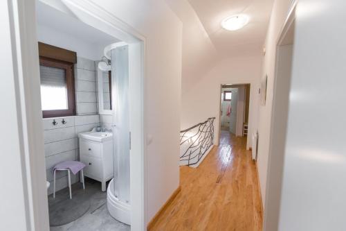 a white bathroom with a sink and a toilet at Jezerska Villa in Ogulin