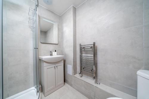 a bathroom with a sink and a toilet and a mirror at 2 Bed Flat in Woking Central in Woking