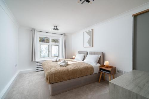 a white bedroom with a bed and two windows at 2 Bed Flat in Woking Central in Woking