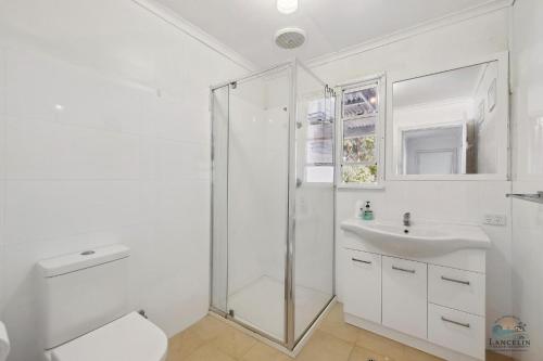 a white bathroom with a shower and a sink at Barefoot on O'Neil in Lancelin