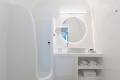 a white bathroom with a sink and a mirror at Nevma Suites in Firostefani