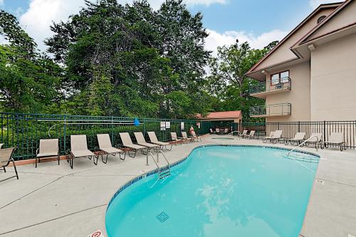 a swimming pool with chairs and a building at Downtown Summit Manor Sleeps 8 Mtn Views Pool in Gatlinburg