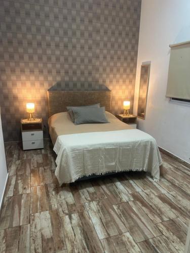 a bedroom with a bed and two night tables with lamps at Aquí es 1!! in Banfield