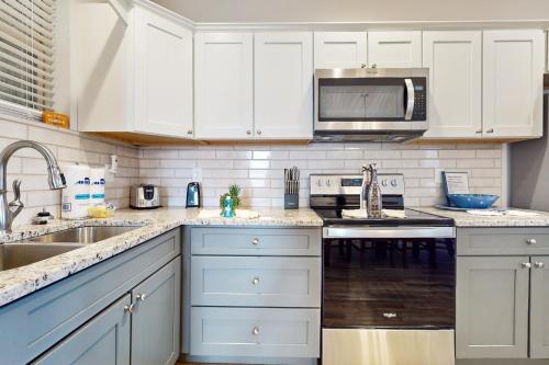 a white kitchen with a sink and a microwave at Pristine & Peaceful Condo Sleeps 6 Shared Pool & Townsend Timbers in Townsend