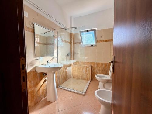 a bathroom with a sink and a toilet and a shower at Hotel Amaiià in Sarandë