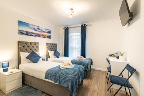a bedroom with two beds and a desk at Prestige Guest House Cambridge Modern Ensuite Rooms in Cambridge