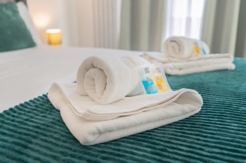 a pile of towels sitting on top of a bed at Prestige Guest House Cambridge Modern Ensuite Rooms in Cambridge