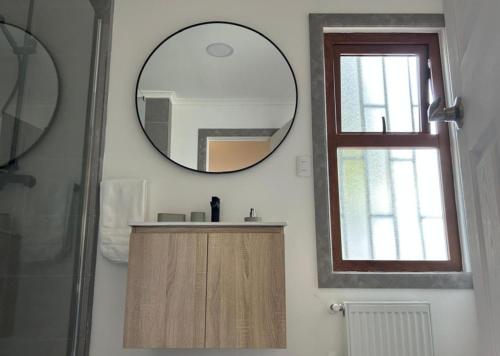 a bathroom with a mirror and a sink and a window at Next Door in Punta Arenas