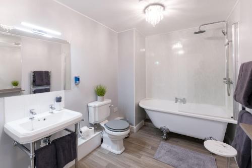 a white bathroom with a tub and a toilet and a sink at Sporting Lodge Inn Middlesbrough in Middlesbrough