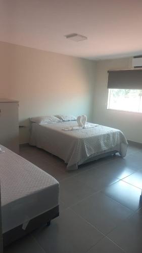 a white bedroom with a bed and a window at Litoral suítes in Araruama