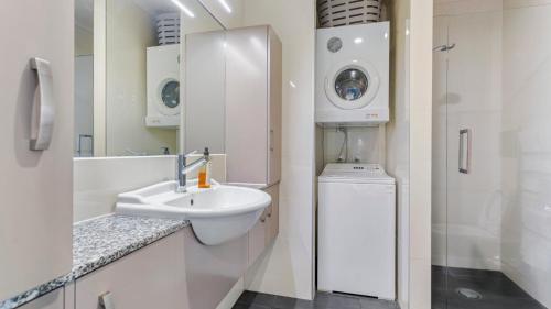 a bathroom with a sink and a washing machine at QV Stays Elegant Modern Apartment with Water Views in Auckland