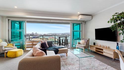 a living room with a tv and a large window at QV Stays Elegant Modern Apartment with Water Views in Auckland