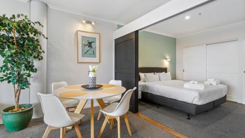 a bedroom with a bed and a table and chairs at QV Stays Elegant Modern Apartment with Water Views in Auckland