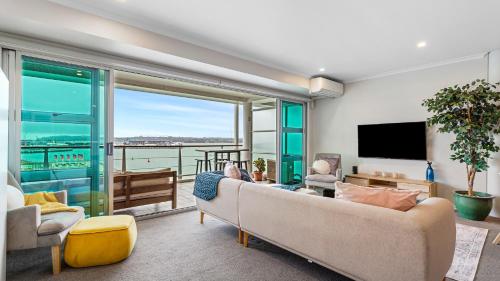 a living room with a couch and a large window at QV Stays Elegant Modern Apartment with Water Views in Auckland