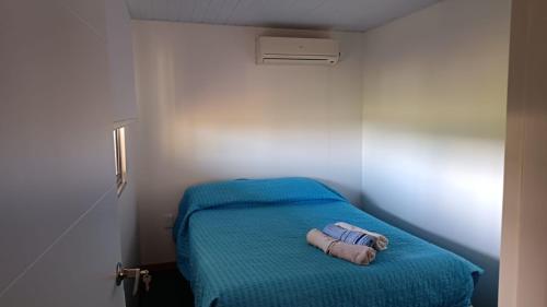 a small room with a bed with a blue blanket at Cabañas El Calabrés in Tacuarembó
