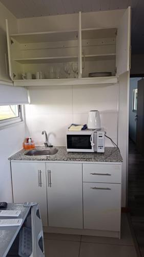 a kitchen with a sink and a microwave on a counter at Cabañas El Calabrés in Tacuarembó