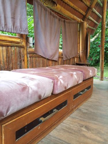 a bed in a wooden house with a window at Cabaña Bugambilla in Macas