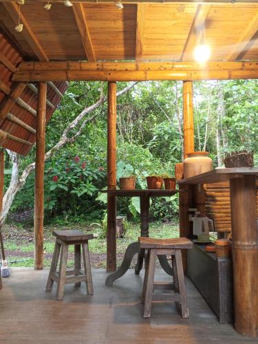 a wooden pavilion with two stools and a table with a stove at Cabaña Bugambilla in Macas