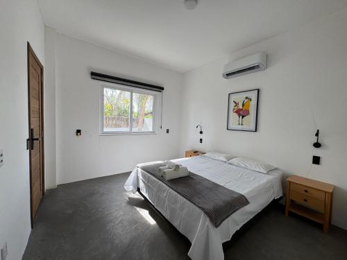 a white bedroom with a bed and a window at Casa Olivia - Eureka in Atins