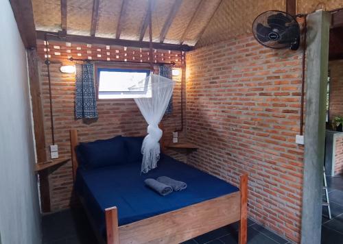 a room with a blue bed in a brick wall at Alam Kita in Karimunjawa