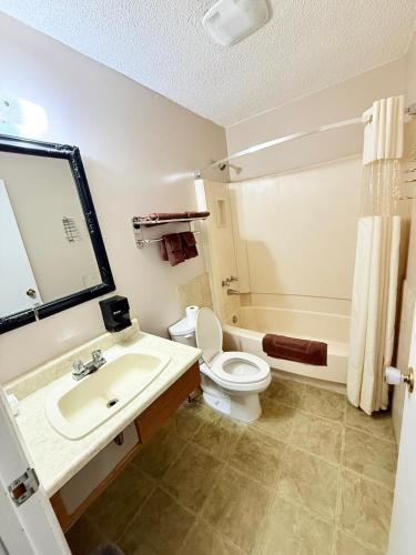 a bathroom with a sink and a toilet and a tub at Melville Country Inn in Melville