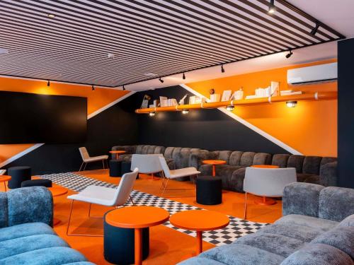 a waiting room with couches and tables and a screen at ibis Styles La Rochelle Centre les Minimes in La Rochelle
