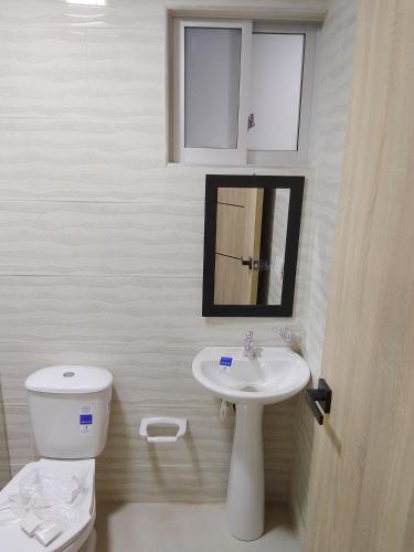 a bathroom with a toilet and a sink and a mirror at Hospedaje Santa Barbara in Tabio