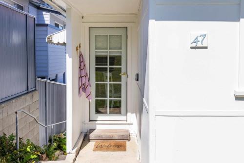 a white front door of a house with a door at Coastal Echo - Oceanstays - Pet Friendly in Yamba