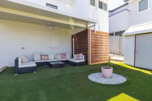 a backyard with a patio with a couch and a table at Coastal Echo - Oceanstays - Pet Friendly in Yamba