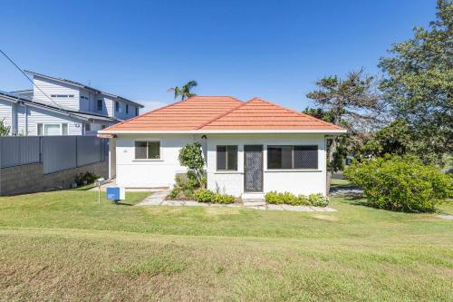 a small white house with an orange roof at Coastal Echo - Oceanstays - Pet Friendly in Yamba