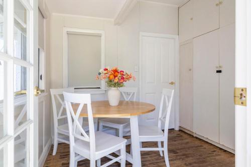 a dining room table with white chairs and a vase with flowers at Coastal Echo - Oceanstays - Pet Friendly in Yamba