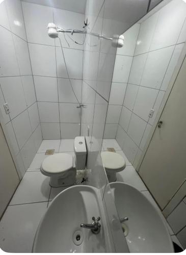 a white bathroom with two toilets and a sink at Pousada 705 Norte 2 in Brasília