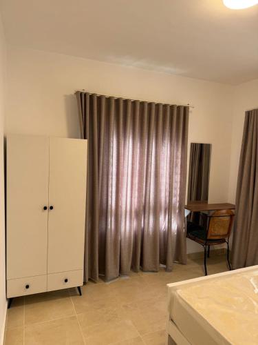a bedroom with a bed and a dresser and curtains at Celia new capital 3 bedrooms in Cairo
