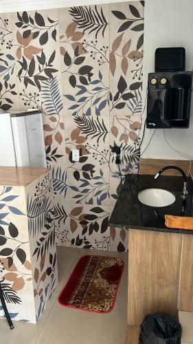 a bathroom with a sink and a wall with floral wallpaper at Pousada 705 Norte 3 in Brasília