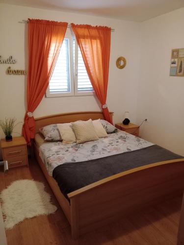 a bedroom with a bed with orange curtains and a window at Apartment Zavalatica 184a in Čara